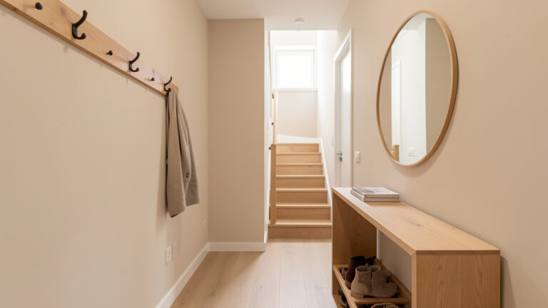 Entrée étroite aménagée avec des rangements compacts et un passage dégagé vers l’escalier.